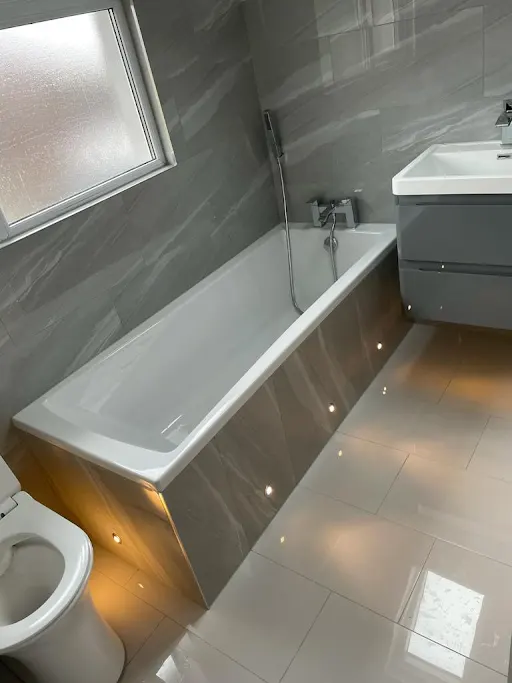 Bathroom installation with bath and warm LED plinth lighting, Bexley